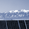 Solar panels in the foreground, snow-capped mountains in the background.