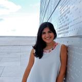 Woman in white dress leaning against a pale colored wall and sky