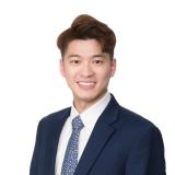 Sam wearing navy blazer and blue tie smiling in front of white background