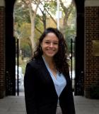 Woman in black blazer smiling in the courtyard of NYU School of Law