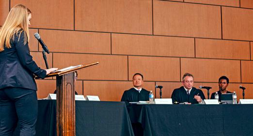 Lauren May at lectern talking to judges